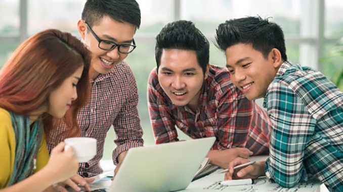 Cheerful Vietnamese colleagues in front of laptop screen